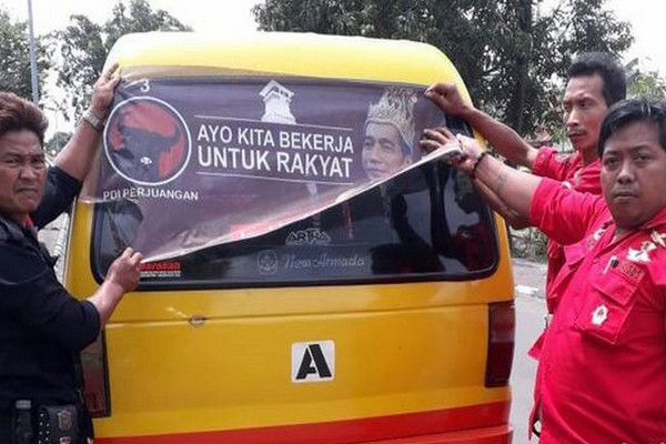 Kader PDIP mencopot stiker "Raja Jokowi" yang menempel di angkot di Purworejo, Senin (12/11). (Foto: detik.com/Rinto H)