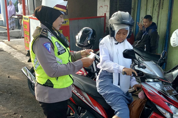 Petugas menilang pelajar yang menggunakan sepeda motor di Kecamatan Panjatan, Kabupaten Kulon Progo, DIY, 26 September 2017. (Foto: Polri)