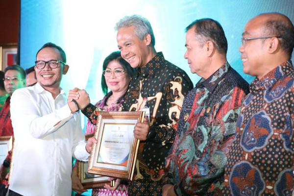 Gubernur Jateng, Ganjar Pranowo (tengah), salam komando dengan Menakertrans Hanif Dhakiri sela penganugerahan penghargaan Integra 2018 di Jakarta, Senin (19/11). (Foto: Pemprov Jateng)