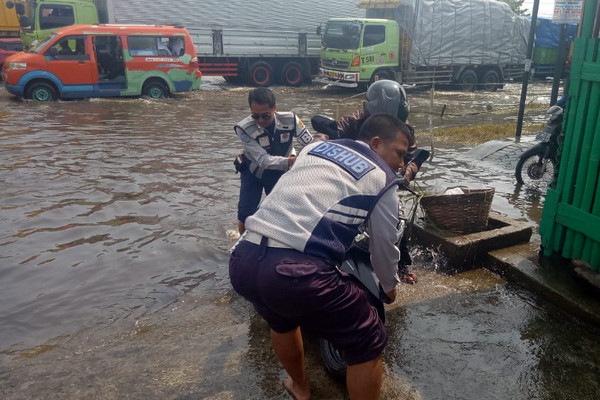  Anggota Dishub Kota Semarang membantu mendorong motor warga yang mogok akibat melintasi banjir di Jalan Kaligawe, Senin (10/12). (Foto: Twitter/@dishubkotasmg)