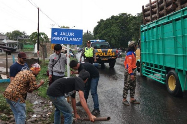 Warga memasang papan petunjuk jalur penyelamat di Jalan Tegal-Banyumas pascakecelakaan di depan RS Muhammadiyah Bumiayu, Selasa (11/12). (Foto: ist)