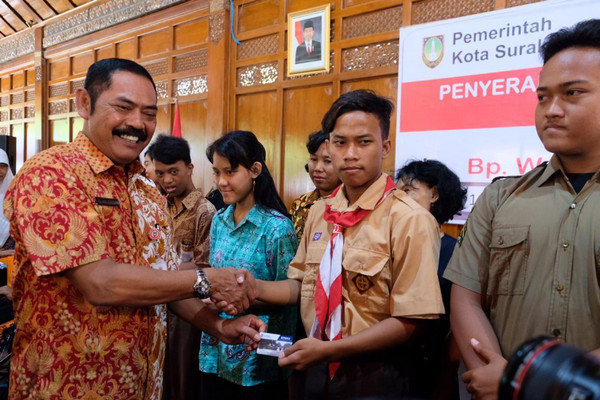 Wali Kota Surakarta, FX Hadi Rudyatmo (kiri), menyerahkan kartu BPMKS ke siswa penerima di Pendhapi Gede Balai Kota, Jumat (16/11). (Foto: Twitter/@PEMKOT_SOLO)