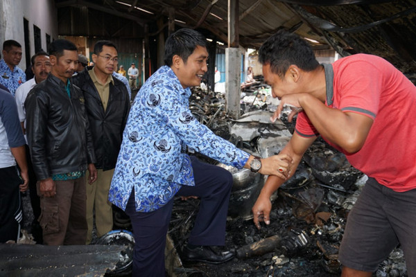 Bupati Magelang, Zaenal Arifin (tengah), berbincang sambil memegang tangan seorang pedagang di Pasar Kaponan yang terbakar, Senin (31/12). (Foto: Pemkab Magelang)