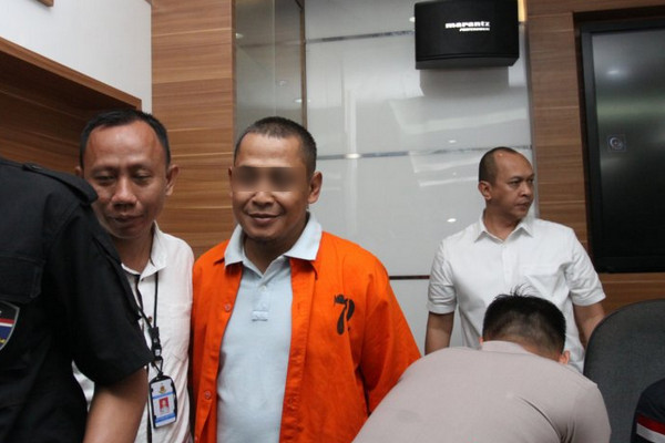 Polisi menggiring pelaku pembuat hoaks tujuh juta surat suara tercoblos, BBP (kemeja oranye), di Mabes Polri, Jakarta, Rabu (9/1). (Foto: Antara Foto/Reno Esnir)