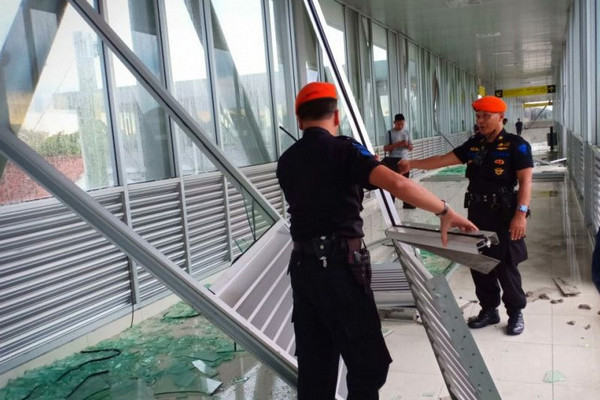 Petugas membersihkan pecahan kaca di skybridge yang menghubungkan Terminal Tirtonadi dengan Stasiun Solo Balapan, Kota Surakarta, Jateng, Jumat (11/1). (Foto: Antara Foto/Aris Wasita)