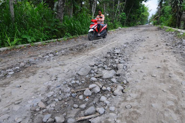 Pengendara motor melintasi jalur evakuasi Merapi yang rusak di Desa Tlogowatu, Kecamatan Kemalang, Kabupaten Klaten, Jateng, Kamis (10/1). (Foto: Antara Foto/AJ Nugroho)