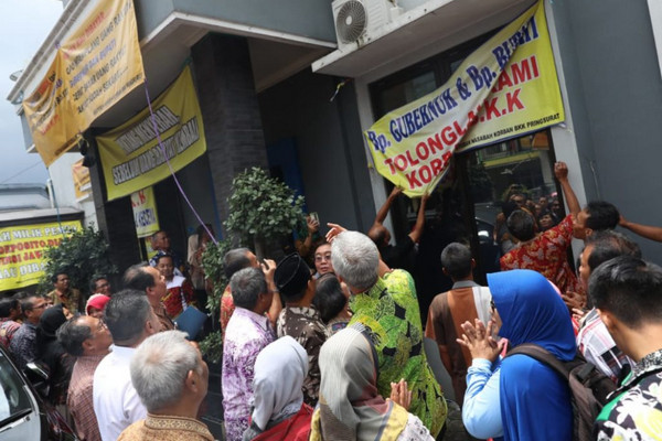 Gubernur Jateng, Ganjar Pranowo (batik hijau), menyaksikan nasabah mencopot spanduk yang terbentang di beberapa sisi Kantor BPR Pringsurat, Kabupaten Temanggung, Jateng, Kamis (31/1). (Foto: Pemprov Jateng)