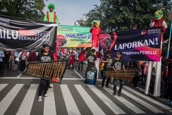 Ilustrasi badut dengan egrang berjalan dan membawa poster sosialiasi kawal Pemilu 2019 saat Hari Bebas Kendaraan Bermotor di Jalan Slamet Riyadi, Kota Surakarta, Jateng, Minggu (24/2). (Foto: Antara Foto/Mohammad Ayudha)