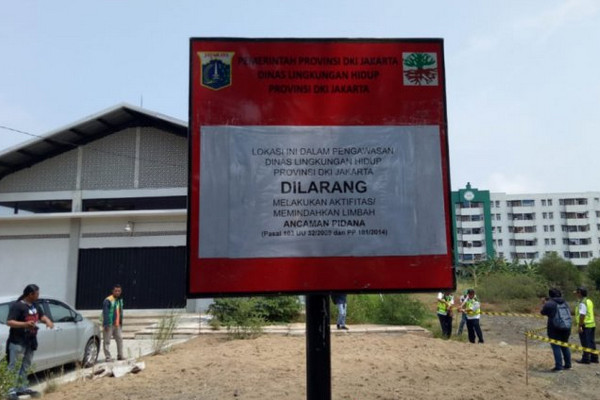 DLH DKI Jakarta memasang garis pengaman dan papan peringatan di tumpukan pasir yang diduga limbah B-3 di Kompleks Rusun Marunda, Jakarta. (Foto: Antara/Fianda Sjofjan Rassat)