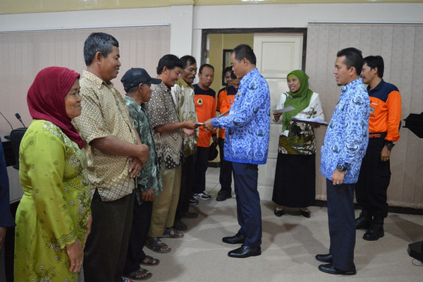 Bupati Karanganyar, Juliyatmono (tengah), menyerahkan bantuan kepada warga yang huniannya rusak akibat bencana alam di Ruang Podang, Kantor Setda Karanganyar, Jateng, 12 November 2015. (Foto: Pemkab Karanganyar)