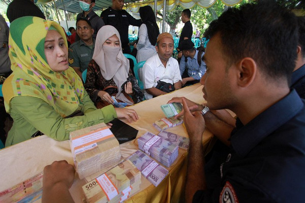 Petugas bank menghitung uang yang akan ditukarkan masyarakat jelang Lebaran di halaman Rumah Jabatan Gubernur Gorontalo di Kota Gorontalo, Gorontalo, 7 Juni 2018. (Foto: Antara Foto/Adiwinata Solihin)