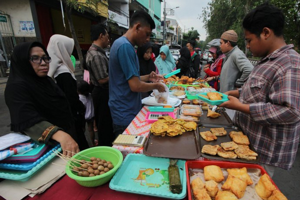 Pedagang melayani pembeli takjil di kawasan wisata religi Masjid dan Makam Sunan Ampel, Kota Surabaya, Jatim, Senin (6/5). (Foto: Antara Foto/Didik Suhartono)