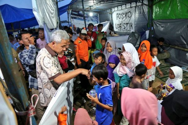 Anak-anak warga Tambakrejo korban penggusuran normalisasi Sungai Banjir Kanal Timur (BKT) menyalami Gubernur Jateng, Ganjar Pranowo (kedua kiri), di tenda pengungsian di Kelurahan Tanjungmas, Kecamatan Semarang Utara, Kota Semarang, Jateng, Senin (13/5). (Foto: Twitter/@kominfo_jtg)