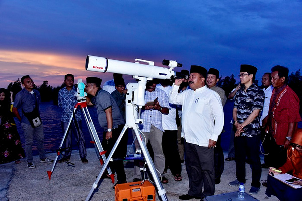 Bupati Bengkalis, Amril Mukminin (kokoh putih), memantau hilal melalui teleskop untuk menentukan awal 1 Ramadan 1440 H di Pantai Selat Baru, Kecamatan Bantan, Kabupaten Bengkali, Riau, Minggu (5/5). (Foto: Pemkab Bengkalis)
