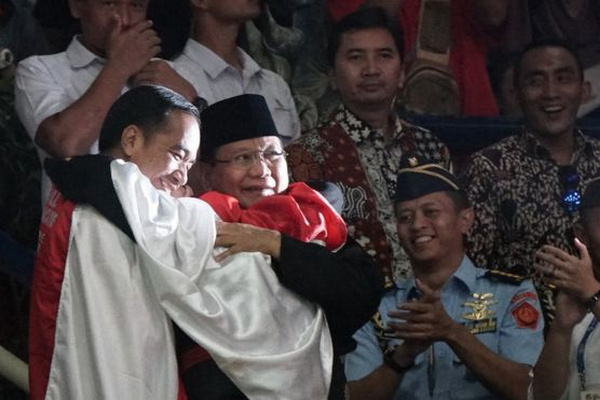 Presiden Jokowi (kiri) dan Ketua Umum IPSI, Prabowo Subianto, berpelukan dan mengapit pesilat Yudani Kusumah Hanifan (berbalut bendera merah-putih), usai memenangkan medali emas ke-29 Indonesia di Asian Games 2018 di di Padepokan Pencak Silat TMII, Jakarta, 29 Agustus 2018. (Foto: Antara Foto/Aditia Noviansyah)