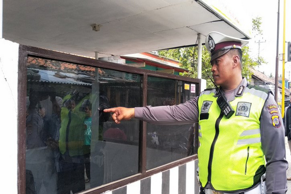 Polisi menunjukkan kerusakan di kaca pos polisi yang menjadi sasaran teror di Desa Tawangsari, Kecamatan Pengasih, Kabupaten Kulon Progo, DIY. (Foto: Antara/Sutarmi)
