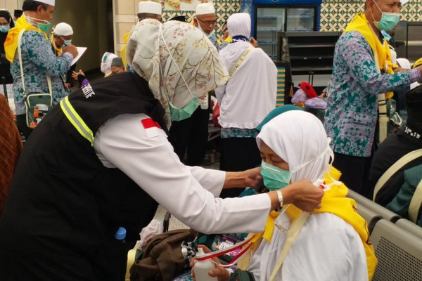 Petugas kesehatan melayani jemaah haji Indonesia untuk menggunakan alat pelindung diri. (Foto: Kemenkes)