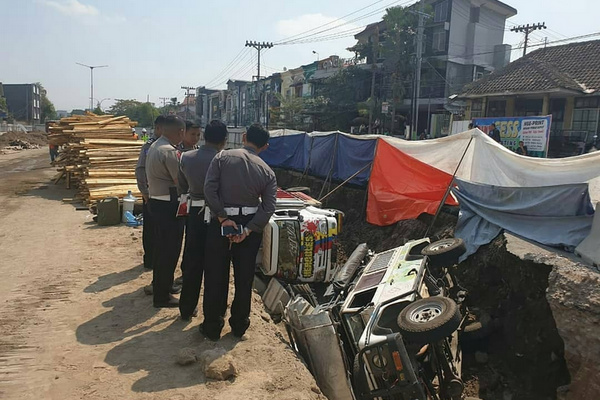Petugas meninjau lokasi terperosoknya dua kendaraan ke lubang proyek lintas bawah Kentungan di Kabupaten Sleman, DIY, Selasa (23/7). (Foto: Instagram/@polressleman)