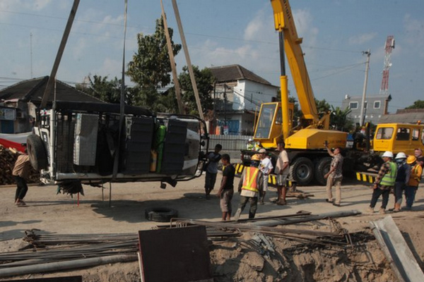 Pekerja mengevakuasi mobil yang terperosok ke dalam lubang di sekitar proyek jalan layang Kentungan, Kabupaten Sleman, DIY, Selasa (23/7). (Foto: Antara Foto/Oky)