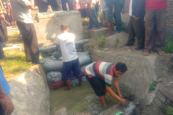 Warga menutup saluran irigasi di Jalan Karangnongko, Kelurahan Panggungharjo, Kecamatan Sewon, Kabupaten Bantul, DIY, Kamis (25/7). (Foto: GATRA/Kukuh Setyono)