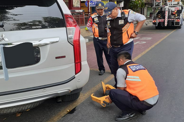 Petugas Dishub hendak menggembok ban mobil yang kedapatan parkir sembarangan di Kota Surakarta, Jateng. (Foto: Twitter/@dishubsurakarta)