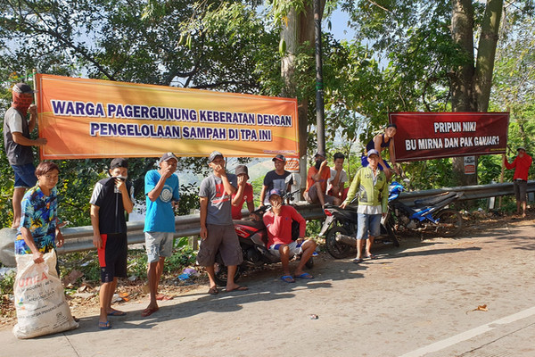 Warga Desa Pagergunung memasang spanduk protes pengelolaan sampah di TPA Pagergunung, Kabupaten Kendal, Jateng, Minggu (28/7). (Foto: Twitter/@HertantoSigit)