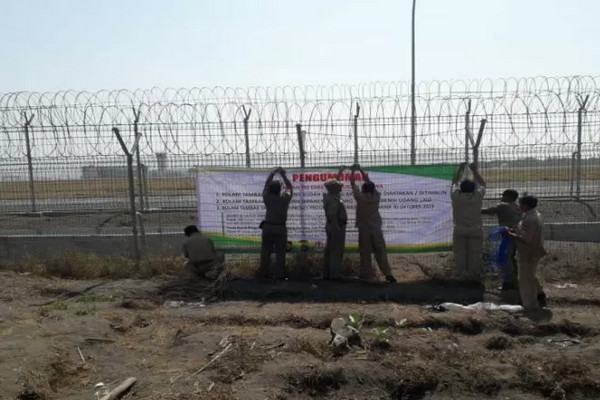 Personel Satpol PP memasang pengumuman tenggat waktu pengosongan lahan tambak udang di selatan Bandara Internasional Yogyakarta, Kecamatan Temon, Kabupaten Kulon Progo, DIY. (Foto: Antara/Sutarmi)