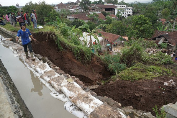Seorang relawan melintasi tanggul darurat yang dipasang di lokasi longsor tanggul irigasi di Kelurahan Parakancanggah, Kabupaten Banjarnegara, Jateng, Sabtu (2/11). (Foto: Antara Foto/Idhad Zakaria)