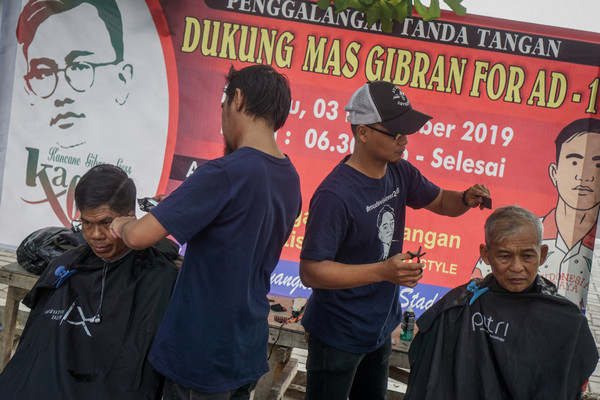 Warga memotong rambut saat acara potong rambut gratis dan tanda tangan dukungan untuk Gibran pada Pilkada 2020 di Solo, Jawa Tengah, Minggu (3/11/2019). Kegiatan tersebut sebagai dukungan kepada putra Presiden Joko Widodo, Gibran Rakabuming Raka yang akan maju pada Pemilihan Walikota Solo 2020. (Foto&keterangan: Antara Foto).
