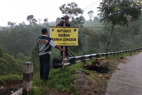 Petugas Dishub Jateng memasang papan pengumuman rawan longsor di salah satu ruas jalan. (Foto: Facebook/@perhubunganjtg)