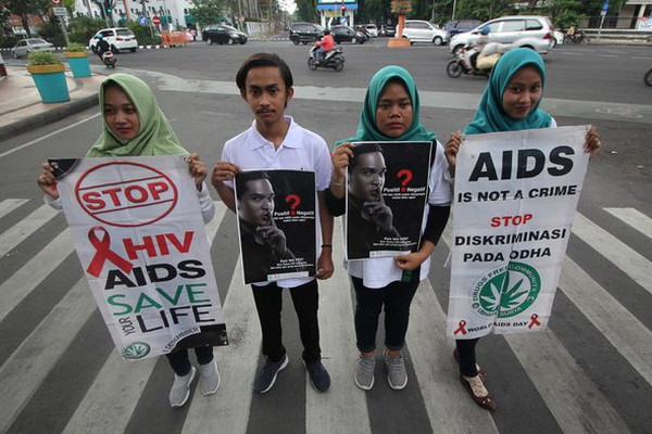 Mahasiswa Universitas Bhayangkara Surabaya membentangkan poster saat melakukan aksi peringatan Hari AIDS Sedunia di Kota Surabaya, Jatim, 1 Desember 2018. (Foto: Antara Foto/Moch. Asim)