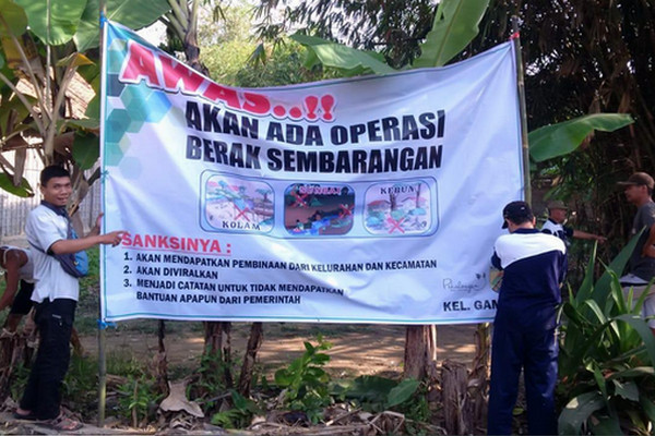 Petugas memasang spanduk sosialisasi operasi BAB sembarangan di Kelurahan Gamer, Kecamatan Pekalongan Timur, Kota Pekalongan, Jateng, Jumat (23/8). (Foto: Pemkot Pekalongan)