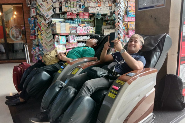 Irfan Hakim menikmati kursi pijat otomatis di Stasiun Gambir.  (Foto: Antara).