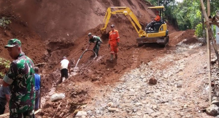 Alat berat dan para relawan menyingkirkan longsoran tanah dari badan jalan di Dusun Gunung Alang, Banjarnegara, Kamis (2/1). ANTARA