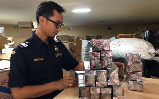 Seorang pegawai Kantor Pengawasan dan Pelayanan Bea dan Cukai (KPPBC) Tipe Madya Cukai Kudus, Jawa Tengah, menunjukkan barang bukti rokok ilegal, Rabu (29/01). (ANTARA)