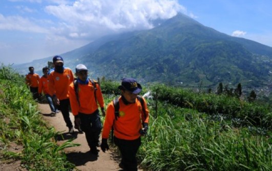 Petugas melintasi jalur pendakian dengan berlatar belakang Gunung Merbabu di Selo, Boyolali, Jawa Tengah. (ANTARA)