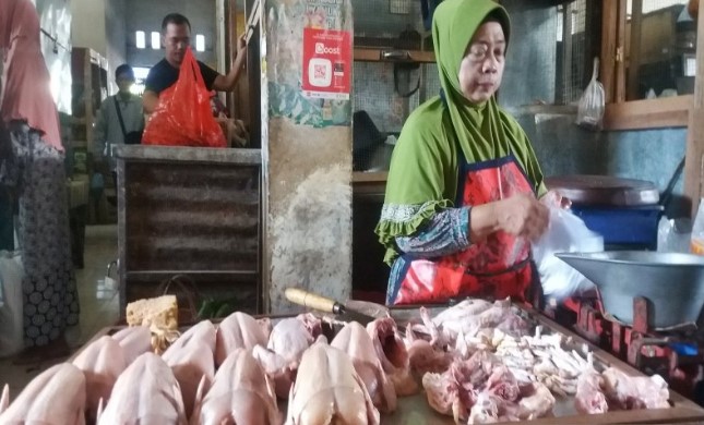 Seorang pedagang daging ayam saat melayani pembeli di Pasar Tradisional Sidodadi Kleco Solo, Jateng, Jumat (17/04). (ANTARA)