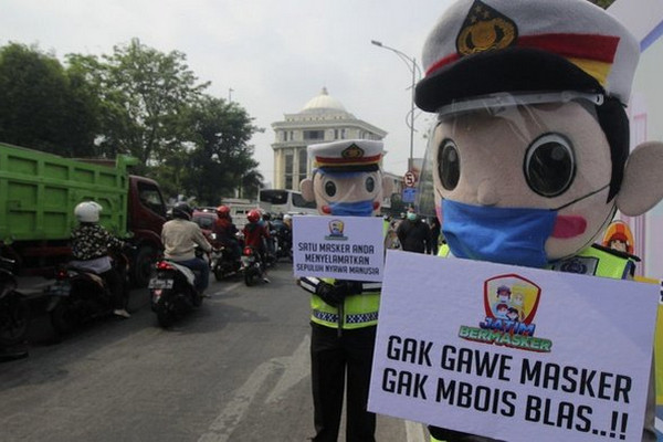 Personel kepolisian menyosialisasikan bahaya Covid-19 kepada pengendara di perbatasan Kota Surabaya, Jatim. Foto Antara/Didik Suhartono