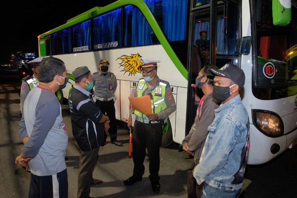 Polisi meminta keterangan sopir dan penumpang bus yang akan mudik saat operasi pengamanan dan penyekatan Covid-19 di Kabupaten Badung, Bali, Minggu (3/5/2020). Foto Antara/Nyoman Hendra Wibowo