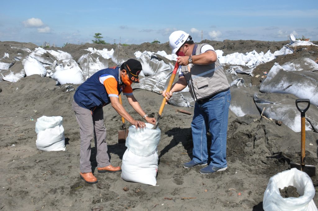 Kepala BPBD Kabupaten Cilacap, Wijonardi (kiri) dan Kepala Dinas PSDA Kabupaten Cilacap, Saeful Hidayat menyiapkan karung pasir di Pantai Lengkong. Foto: cilacapkab.go.id