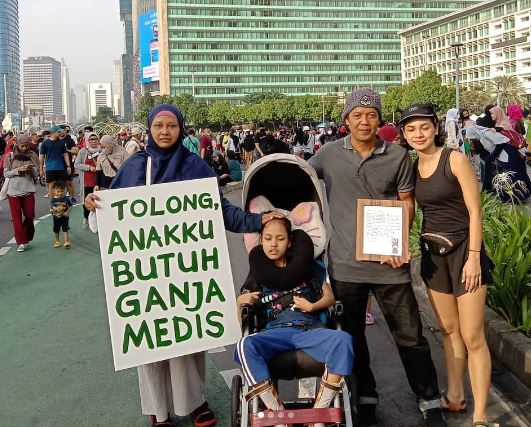 Santi Warastuti bersama anaknya berfoto membentangkan permintaan legalisasi ganja untuk pengobatan di CFD Jakarta. Foto: instagram @santiwarastutisanti